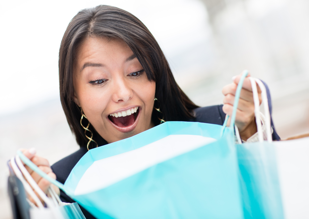 Surprised shopping woman checking her bags and smiling